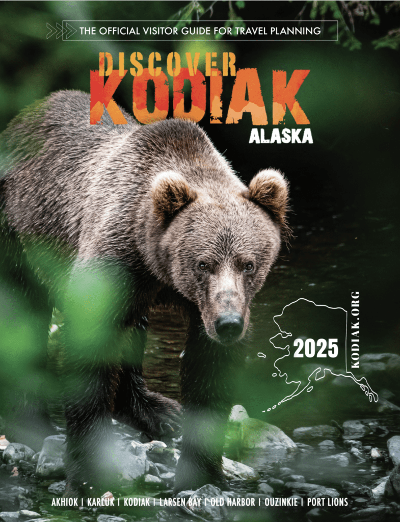 A brown bear stands in a stream surrounded by green foliage. The text reads Discover Kodiak Alaska 2025, featuring a map of Kodiak and Alaska with a list of local communities at the bottom.
